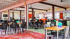 A spacious restaurant with high ceilings and exposed beams, featuring multiple dining tables and chairs.
