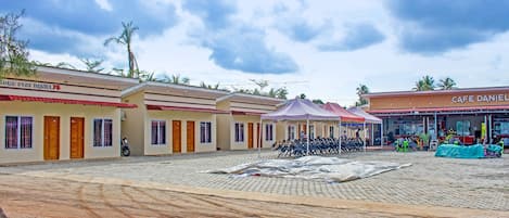 A hotel courtyard with multiple rooms, a covered seating area, and a cafe.
