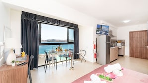 A modern hotel room with a balcony, a dining area, a kitchen, and a bed with towels. - Islet Promenade Studio with Hot Tub and Panoramic Sea Views by GetawaysMalta (St. Paul's Bay)