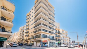 A multi-story building with balconies, a body shop, and a restaurant on the ground floor. - Islet Promenade Studio with Hot Tub and Panoramic Sea Views by GetawaysMalta (St. Paul's Bay)