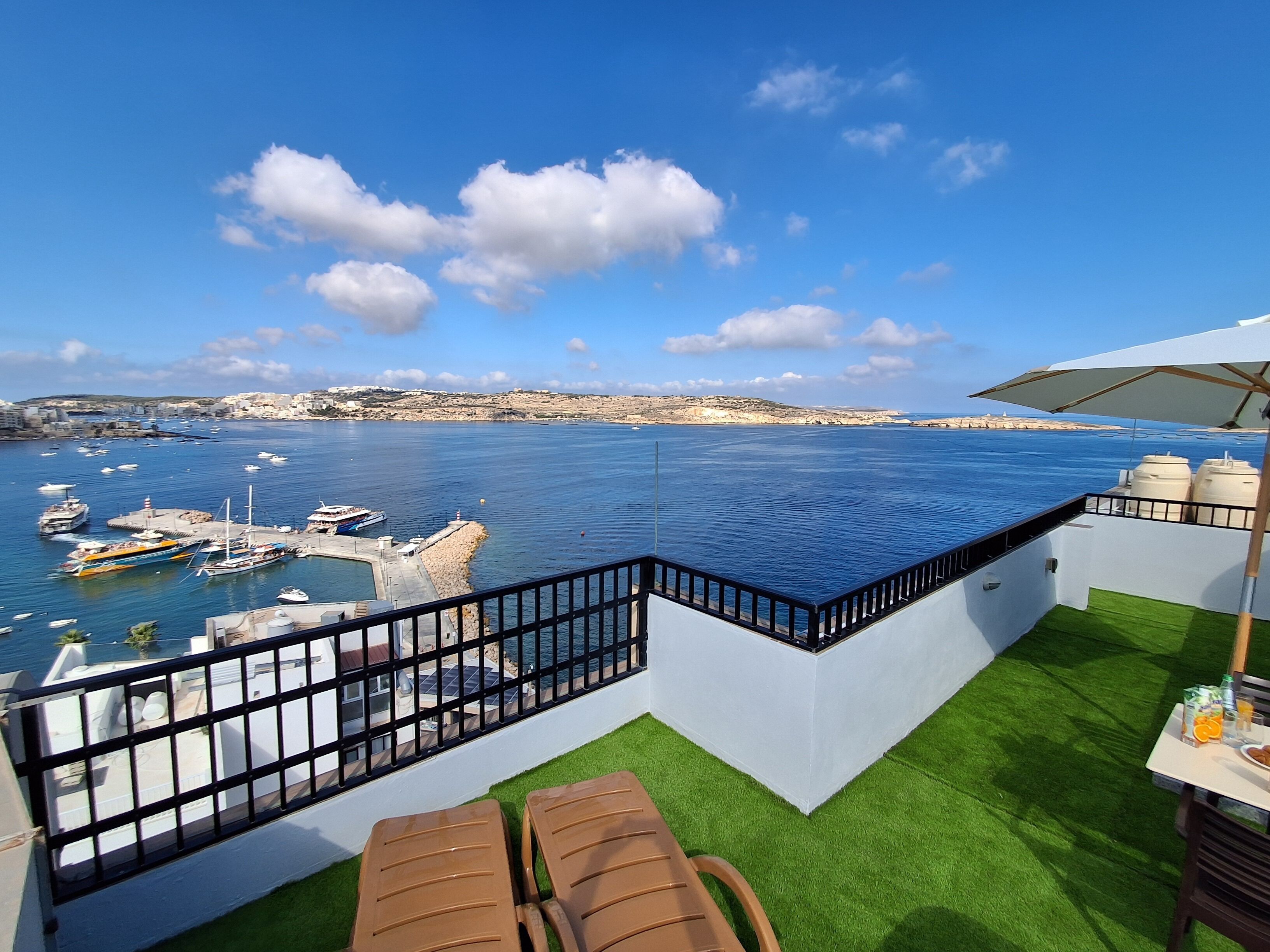Terraza con vistas al mar, que incluye una piscina, césped artificial y mobiliario de exterior.