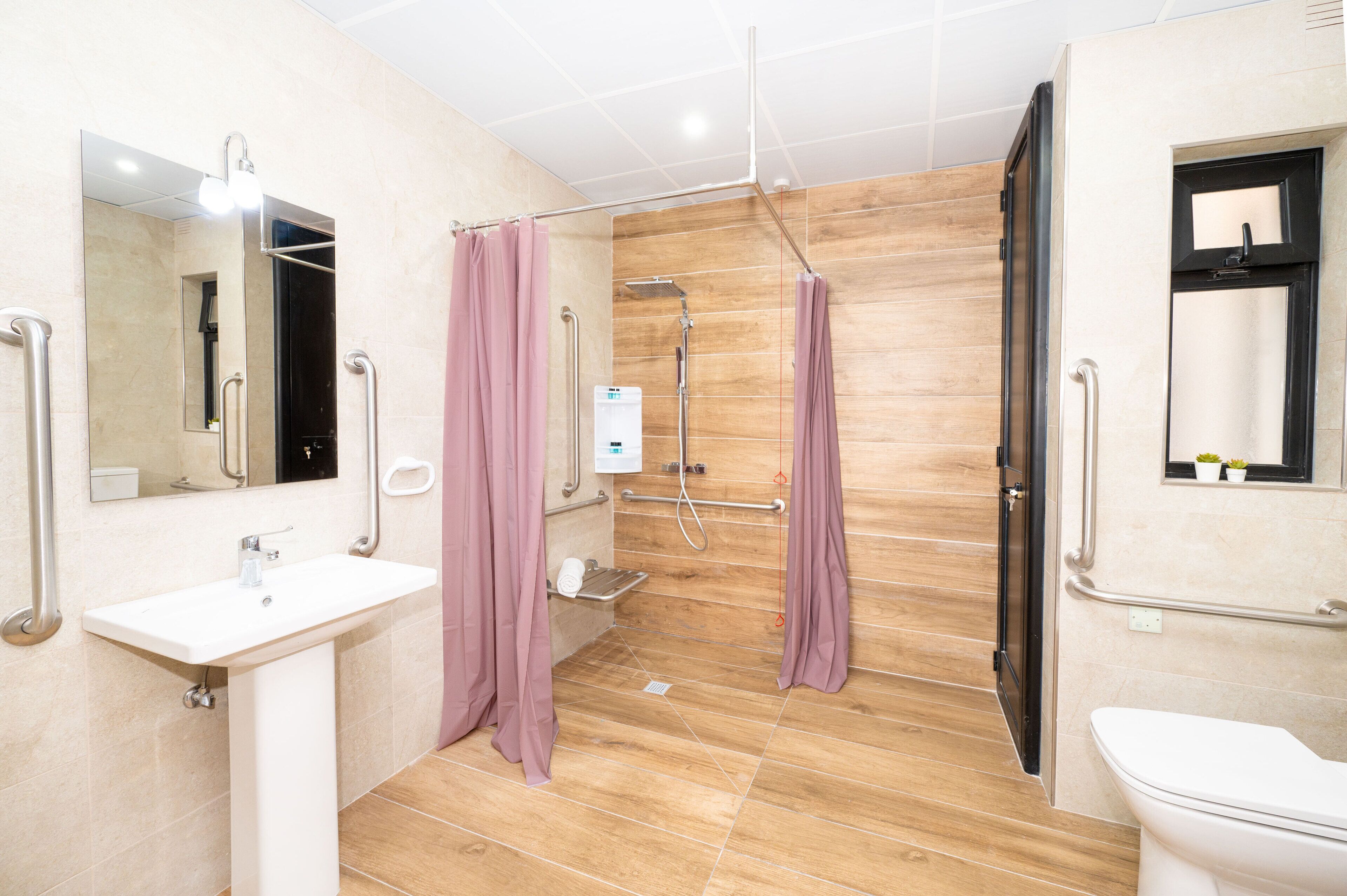 A modern bathroom with a sink, mirror, shower, and toilet.