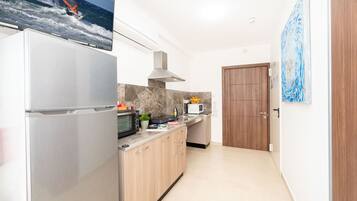 Una cocina moderna con un refrigerador de acero inoxidable, un microondas y armarios de madera.