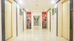 A hotel corridor with a tiled floor, doors on both sides, and promotional banners on the walls. - Capital O 91651 Independent99 Near Kalibata city square (Jakarta)