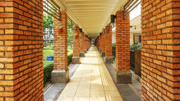A covered corridor with brick columns and a tiled floor. - Capital O 91651 Independent99 Near Kalibata city square (Jakarta)