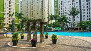 A pool area with a stone pathway, potted plants, and a wooden pergola. - Capital O 91651 Independent99 Near Kalibata city square (Jakarta)