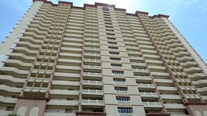A high-rise hotel with multiple balconies, a central entrance, and a blue awning.
