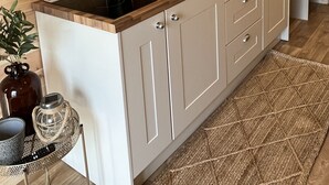 Een moderne keuken met houten lambrisering, een houten aanrecht, een spoelbak en een potplant.