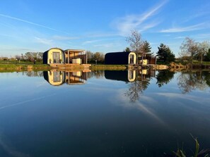 Un entorno tranquilo junto al lago con edificios modernos de forma abovedada reflejándose en el agua.
