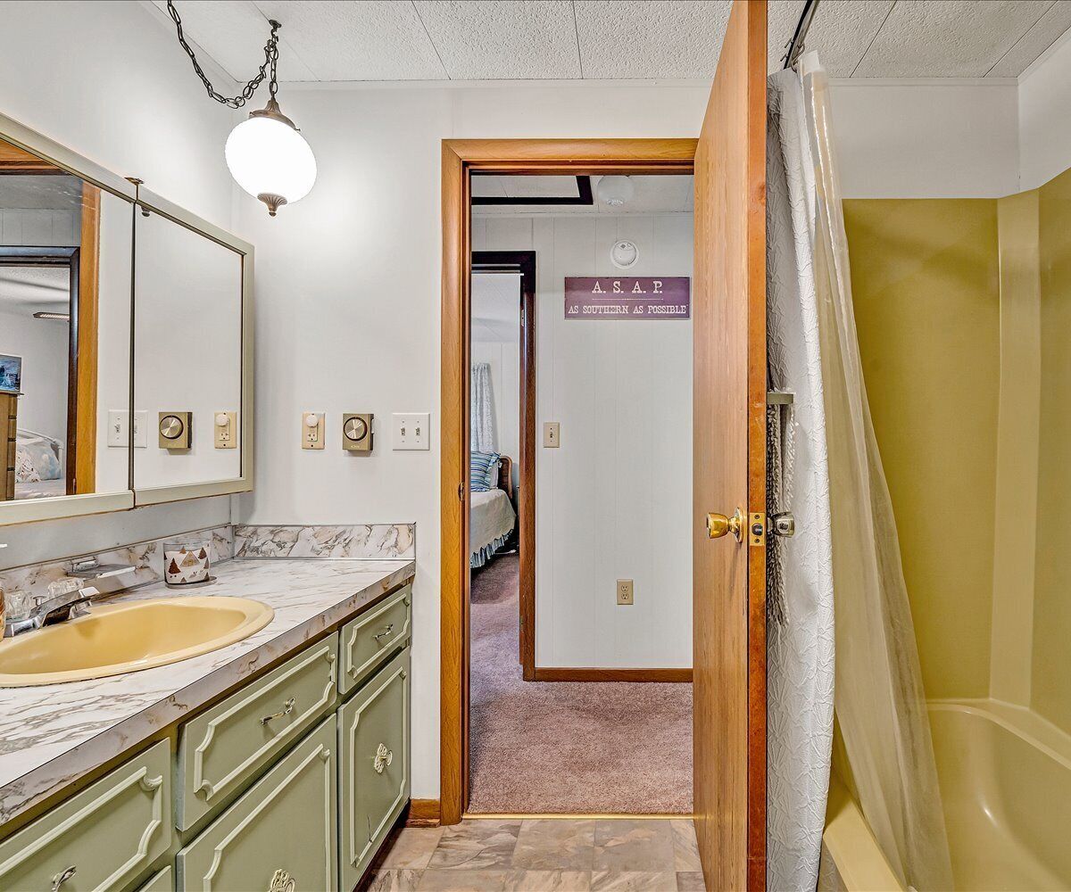 A bathroom with a sink, mirror, and shower curtain.