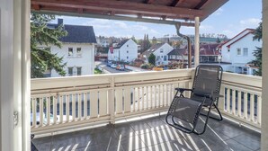 Un balcone coperto con una sedia e vista su una zona residenziale, sotto un cielo sereno.