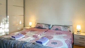Un letto matrimoniale con biancheria da letto decorata, due abat-jour e un armadio.