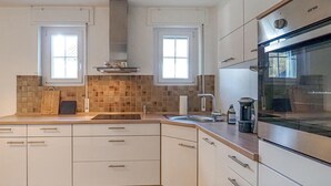 Una cucina moderna con mobili bianchi, un forno in acciaio inossidabile e una finestra sopra il lavello.