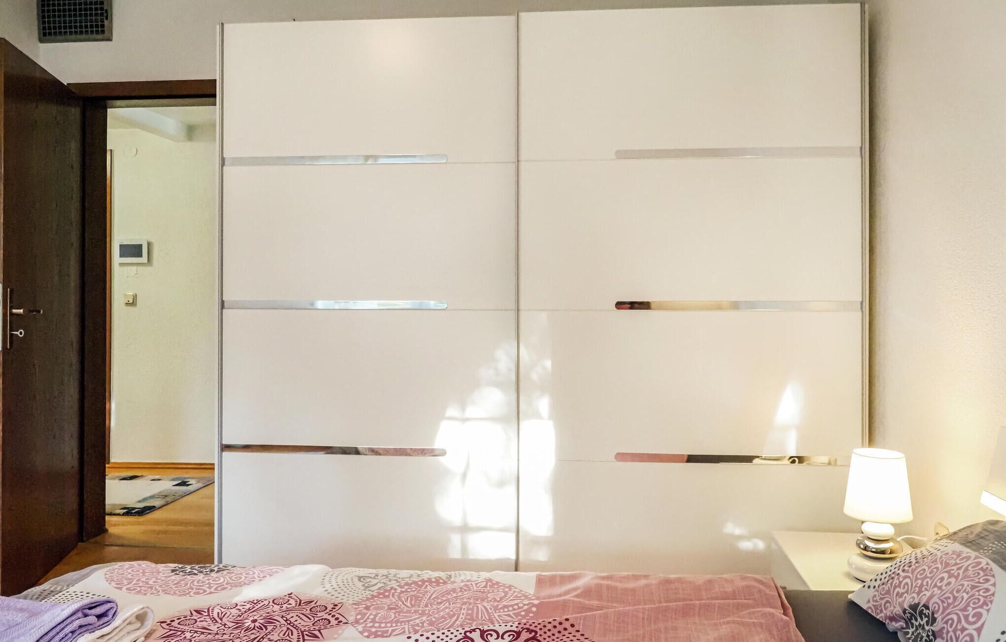Ein Schlafzimmer mit Bett, Nachttisch mit Lampe und Kleiderschrank.