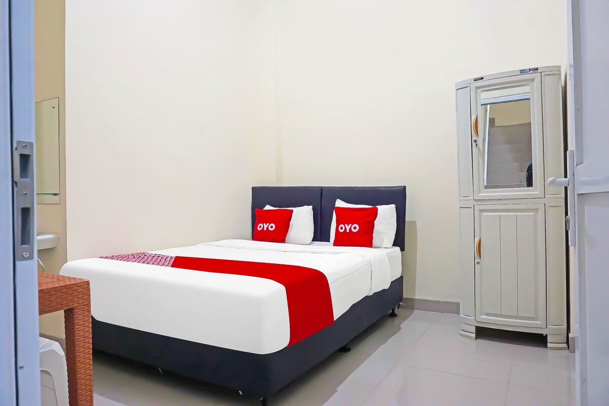 A neatly arranged bedroom with a bed, a wardrobe, and a small table.