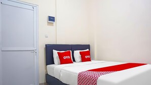 Une chambre d’hôtel avec un lit, une porte blanche et un petit panneau accroché au mur.