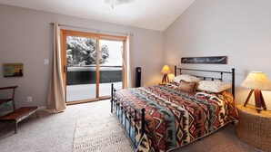 Een slaapkamer met een groot bed, een plafondventilator, een raam met gordijnen, een bedlampje en een welkomstbord.