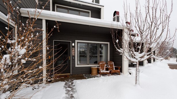 Een tweelaags huis met een sneeuw bedekte veranda en een zichtbare schoorsteen.