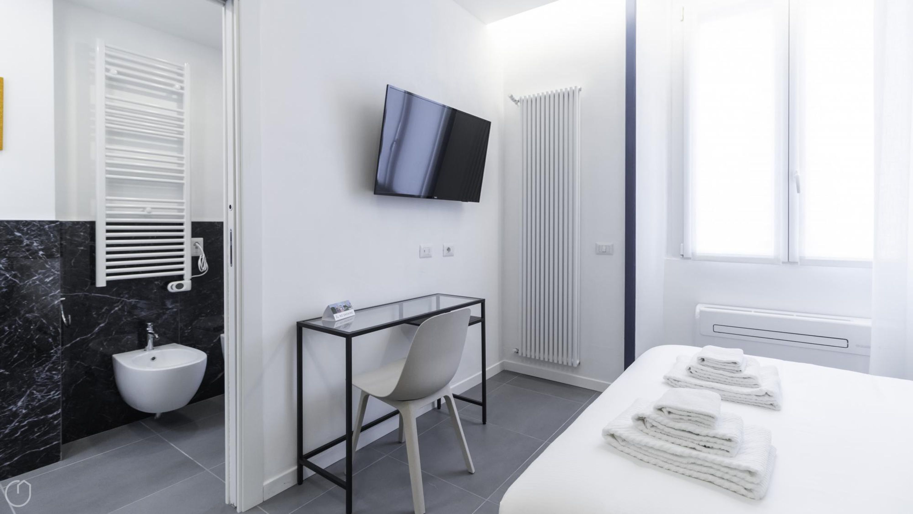 A modern bathroom with a toilet, bidet, and a glass table with a chair.