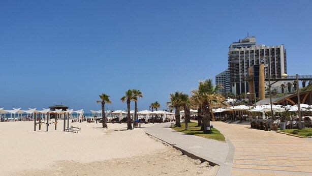 A beachside promenade with palm trees, beach umbrellas, and a modern hotel in the background. - Ramat Yam Marine in Herzliya (Herzliya)