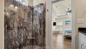A modern bathroom with a glass shower enclosure and a wooden floor.