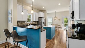 A modern kitchen with a central island, white cabinets, and a blue accent wall.
