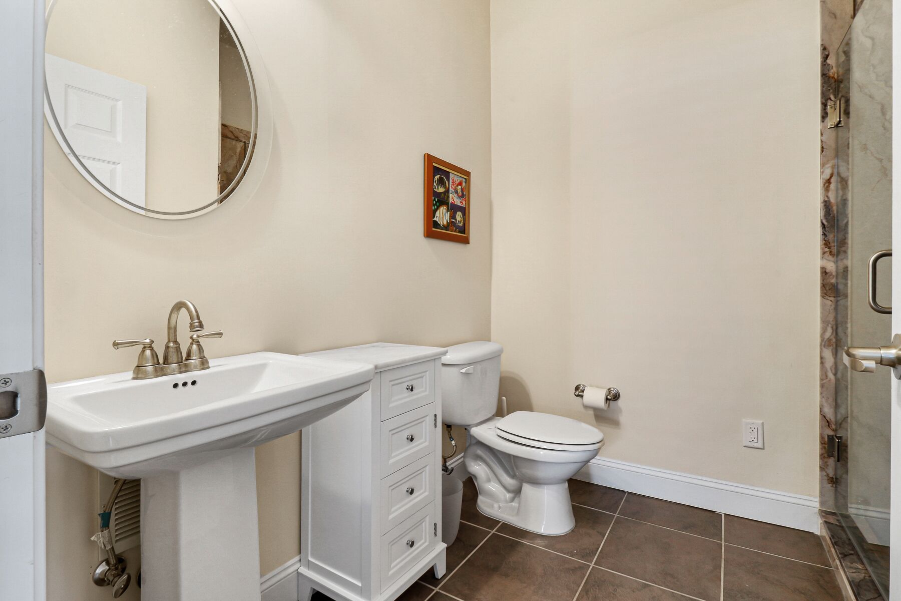 A bathroom with a white vanity, a toilet, and a shower area.