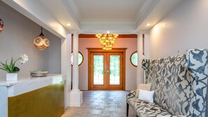 A reception area with a marble counter, a patterned sofa, and a chandelier. - Waterfront LUXURY Guesthouse + Spa Amenities, near Martinique Beach (Musquodoboit Harbour)