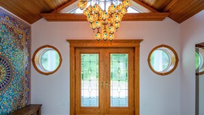 A spacious room with a large wooden door, two round windows, and a colorful tapestry on the left wall. - Waterfront LUXURY Guesthouse + Spa Amenities, near Martinique Beach (Musquodoboit Harbour)