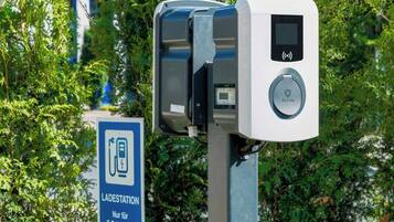 Een parkeerautomaat met een digitaal scherm en kaartlezer, naast een bord dat aangeeft dat deze uitsluitend voor elektrische voertuigen is.