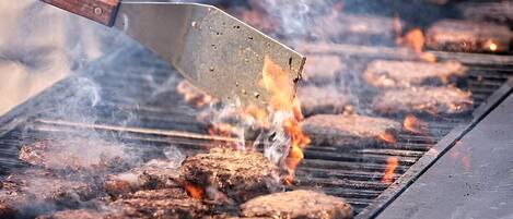 Una parrilla con varias hamburguesas cocinándose.