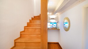 Un escalier en bois mène à un palier où se trouvent un comptoir d’accueil et un miroir décoratif.