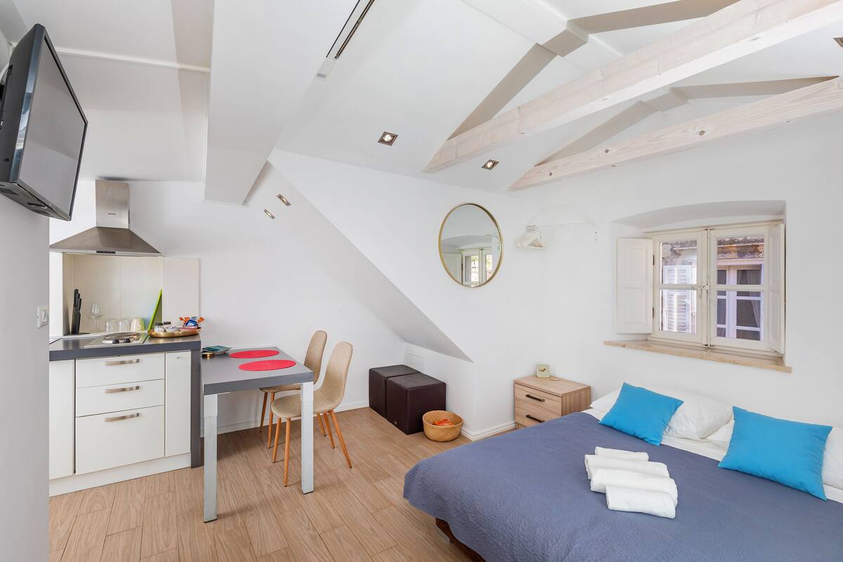 A modern bedroom with a bed, a desk, and a TV.