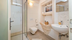 Une salle de bain avec une douche à parois de verre, des toilettes, un lavabo et un miroir.