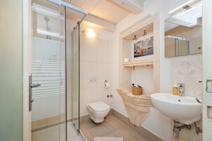 Quarto casal urbano | Banheiro | Chuveiro, toalhas de banho, papel higiênico 