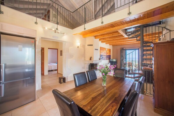 A spacious dining area with a wooden table, chairs, and a vase of flowers.