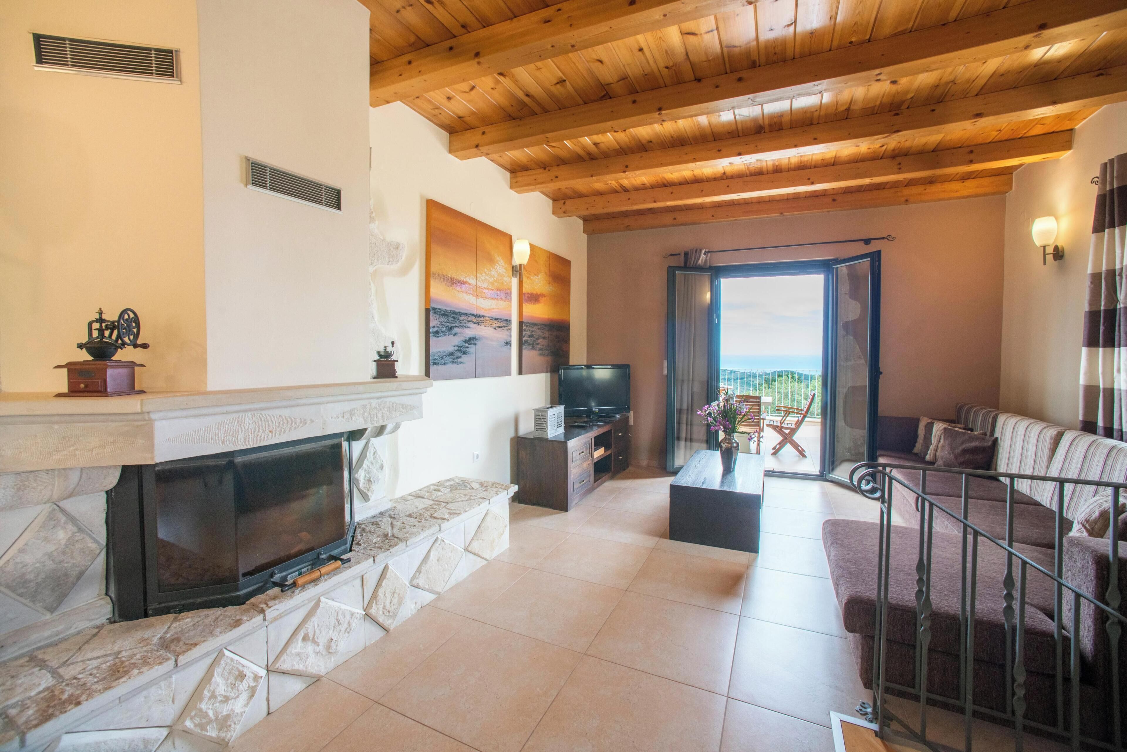A living room with a fireplace, television, and a balcony with a view.