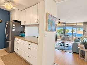 A modern kitchen with white cabinets and a stainless steel refrigerator. - Kamaole Beach Royale #406 Panoramic Ocean View of Kamaole Beach 1, Full A/C (Kihei)