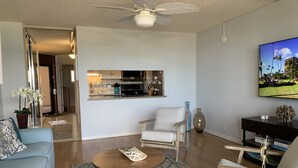 Sala de estar com sofá, poltrona, mesa de centro e TV em um suporte.