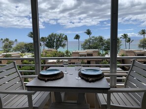 Ein Balkon mit Tisch für zwei Personen mit Blick auf eine Küstenlandschaft, mit Gebäuden und Palmen.