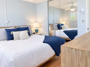 Een slaapkamer met een bed, nachtkastje, lamp en een spiegel.