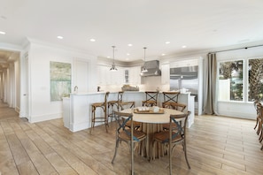 A spacious kitchen with white cabinetry, a central island, and wooden flooring.
