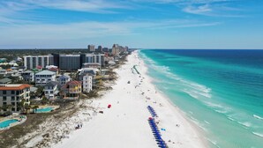 Ein Hotel direkt am Strand mit mehreren Gebäuden, einem Sandstrand und einem klaren, blauen Ozean.