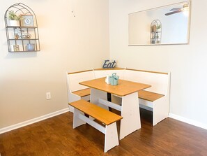 A corner dining area with a wooden table and bench seating. - Newly Furnished Rehoboth Home Close to Everything! (Rehoboth Beach)
