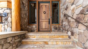Una entrada revestida de piedra con una puerta de madera y escalones que conducen a un porche.