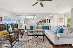 A spacious living room with a large sectional sofa, wicker chairs, and a glass coffee table.