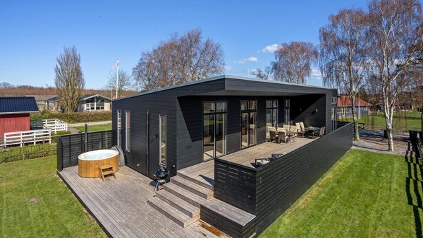 Una casa moderna negra con terraza, jacuzzi y zona de barbacoa.