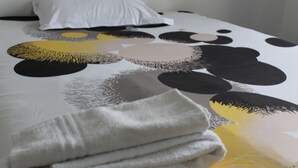 Un lit bien fait, avec une couvre-lit à motifs, un oreiller blanc et une serviette blanche pliée.