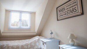 A bedroom with a bed, a nightstand, a lamp, and a window with blinds.
