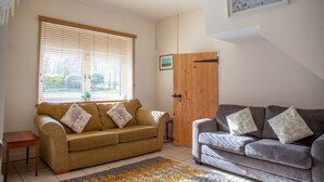 A living room with two sofas, a wooden door, and a window with blinds.